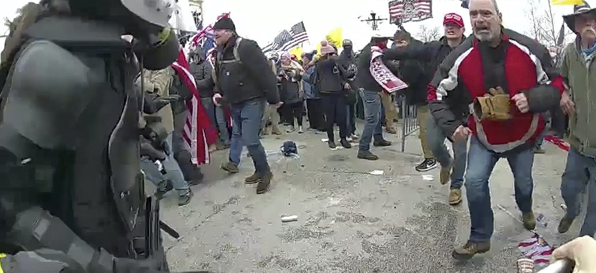 This still frame from Metropolitan Police Department body-worn camera video shows Thomas Webster, in red jacket, at a barricade line at on the west front of the U.S. Capitol on Jan. 6, 2021, in Washington. Webster, a Marine Corps veteran and retired New York City Police Department Officer, is accused of assaulting an MPD officer with a flagpole. 