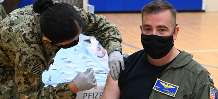 Cmdr. Ronald Cappellini, Naval Air Station Sigonella executive officer, receives his COVID-19 vaccine booster from Lt. j.g. Aracely Duerkop, during a mass-immunization exercise on Naval Air Station Sigonella on Dec. 7. 
