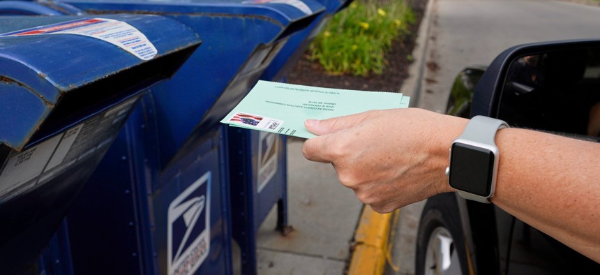 A person drops applications for mail-in-ballots into a mailbox in Omaha, Neb. Data on August 18, 2020.