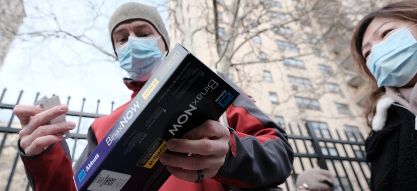 People receive a test kit as City workers hand out take-home Covid-19 test kits in lower Manhattan on December 23, 2021 in New York City. New York City is handing out thousands of the kits, which include two tests per box, in order to lesson the surge of people and long lines at testing sites.