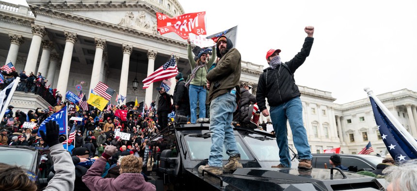 Trump supporters stand on a U.S. Capitol Police armored vehicle as others take over the steps of the Capitol on Jan. 6, 2021.