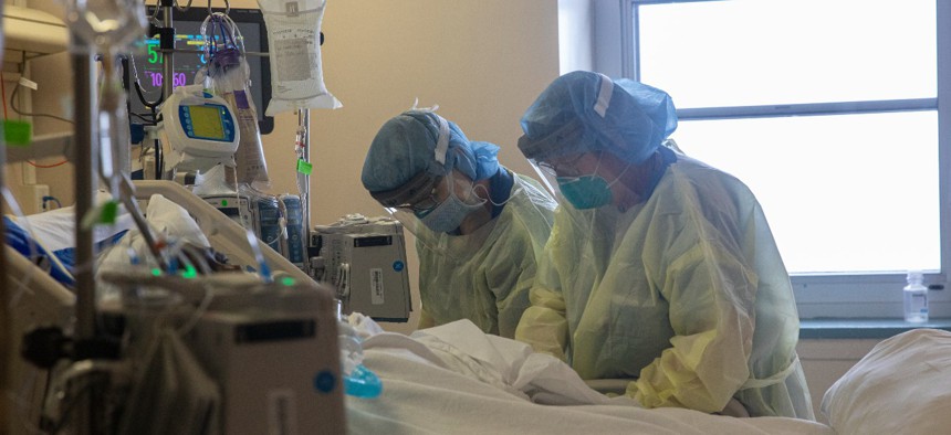 Two nurses assess the vital signs of a COVID-19 patient using a ventilator on the Intensive Care Unit floor at the Veterans Affairs Medical Center on April 21, 2020 in the Brooklyn borough of New York City. 
