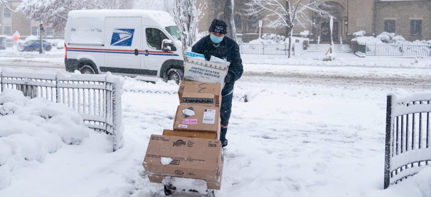 A postal worker pushes packages through the snow on January 3 in Washington, D.C. 