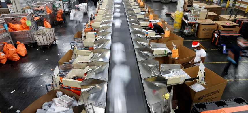 U.S. Postal Service employees sort parcels for distribution inside the Los Angeles Mail Processing & Distribution Center, the largest in the United States, in November 2021. 