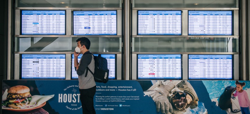 A person speaks on the phone near flight monitors at George Bush Intercontinental Airport in January 2022 in Houston, Texas. 