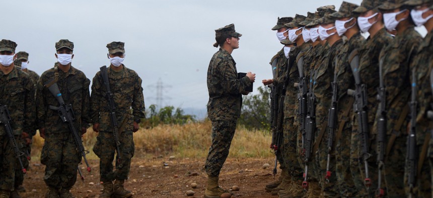A USMC senior drill instructor presents recruits with their Eagle, Globe, and Anchor pin to officially become US Marines on April 22, 2021.