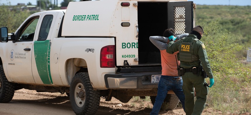 A Border Patrol agent uses personal protective equipment as he prepares to transport two individuals encountered near Naco, Ariz. o