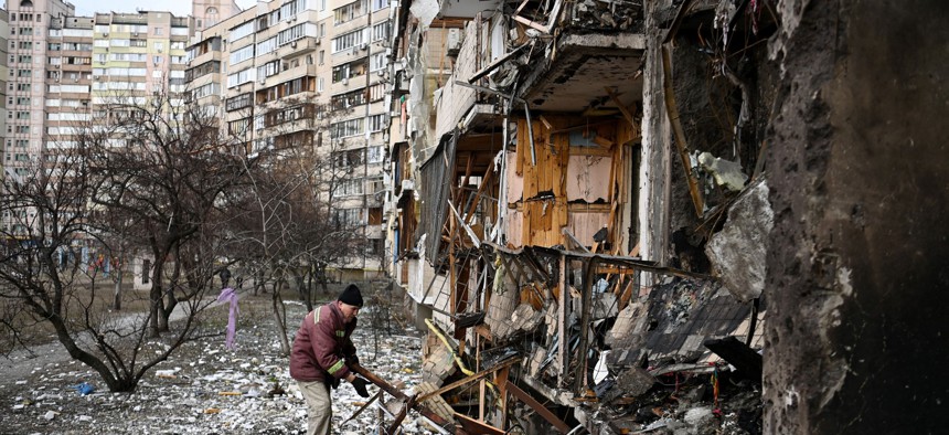 A man clears debris at a damaged residential building at Koshytsa Street, a suburb of the Ukrainian capital Kyiv, where a military shell hit, on February 25.