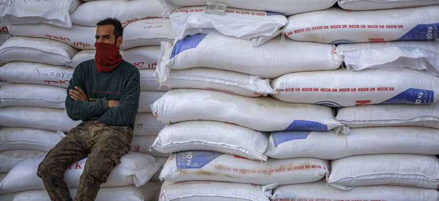 A worker sits next to a pile of flour sacks in Baghdad, Iraq, where wheat prices have surged after the Russian invasion of Ukraine. 