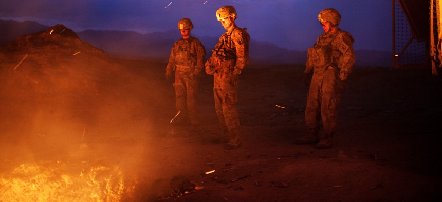 Three soldiers burn trash from the Jaghatu Combat Outpost in a pit, located just outside the walls of the base in Jaghatu, Afghanistan in 2012.