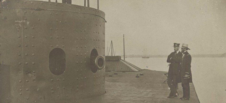 Two men stand on the deck observing the light damage caused to the turret of the ironclad USS Monitor during her fight with the Confederate ironclad CSS Virginia, March 9, 1862, at the Battle of Hampton Roads.