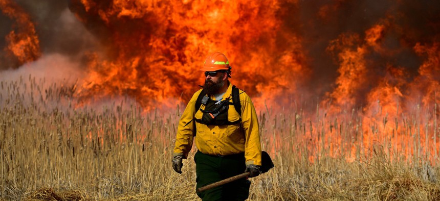 U.S. Fish and Wildfire firefighter Joe Murphy keeps an eye on the fire during a prescribed burn at the Rocky Mountain Arsenal National Wildlife Refuge on April 5, 2021 in Denver. Some federal agencies say they are struggling to compete with state and local governments to hire firefighters.