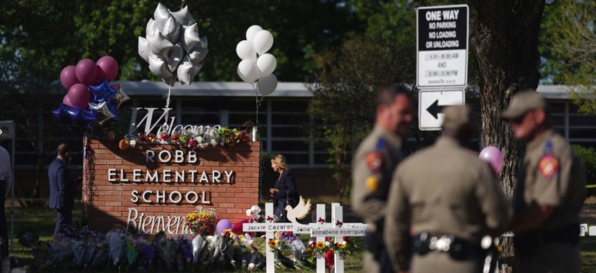 Police officers stand next to a makeshift memorial outside the Robb Elementary School on May 26.