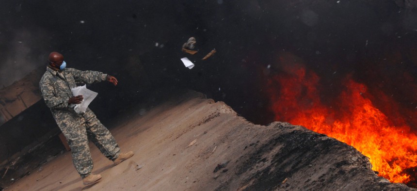 Master Sgt. Darryl Sterling throws unserviceable uniform into a burn pit in Iraq in 2008.