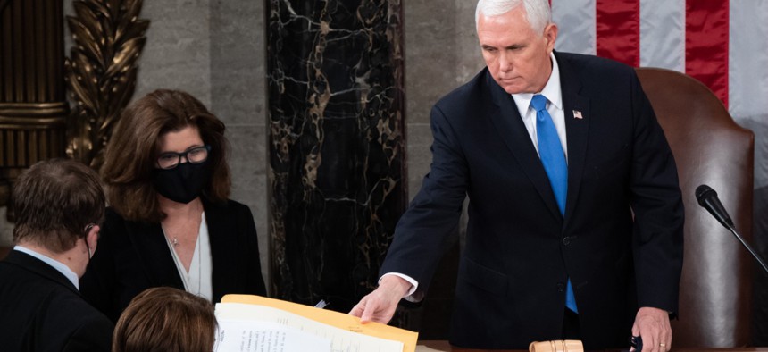 Mike Pence hands the electoral certificate from the state of Arizona to Senator Amy Klobuchar on Jan. 6, 2021.