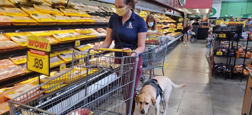 Danyelle Clark-Gutierrez and her service dog, Lisa, shop for food at a grocery store. Clark-Gutierrez got the yellow Labrador retriever to help her cope with post-traumatic stress disorder after she experienced military sexual trauma while serving in the Air Force. 