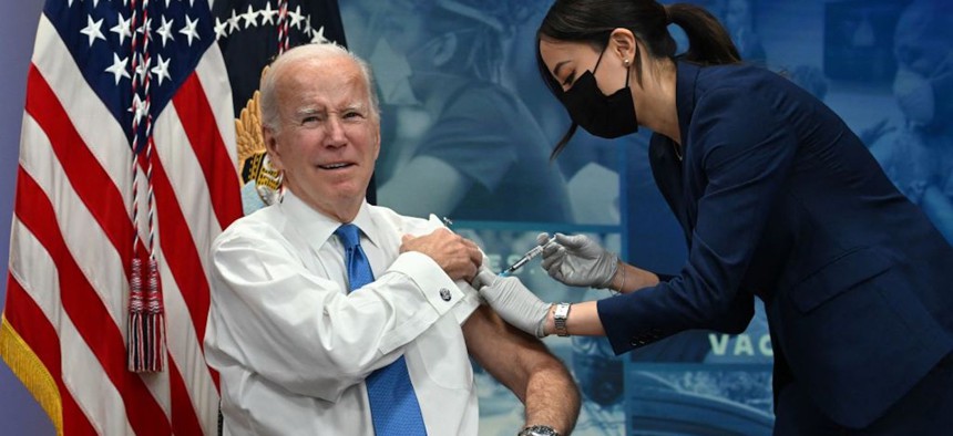 Joe Biden receives the a COVID-19 booster shot in the South Court Auditorium of the Eisenhower Executive Office Building in October.