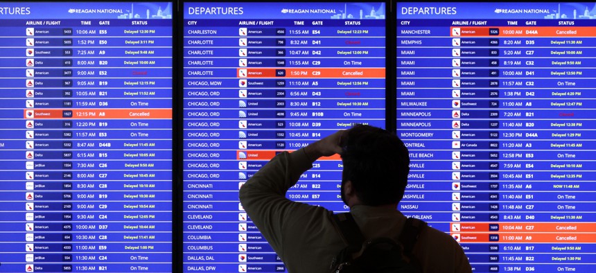 A traveler looks at an information board at Ronald Reagan Washington National Airport on Jan. 11, 2023 after an outage to a key FAA system grounded flights nationwide.