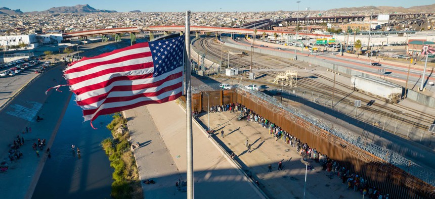 An aerial view of the American flags flying over an international bridge as immigrants line up next to the U.S.-Mexico border fence to seek asylum on December 22, 2022 in El Paso.