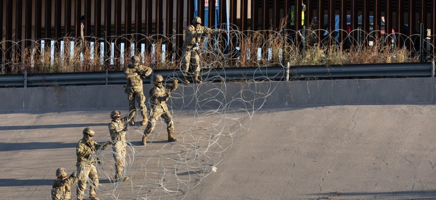 Texas National Guard troops lay down concertina wire to stop migrants from entering a popular crossing area along the bank of the Rio Grande in El Paso, Texas, in December. The Pentagon is sending additional troops to the Southwest border now to help fill “capability gaps” that will not include law enforcement activities. 