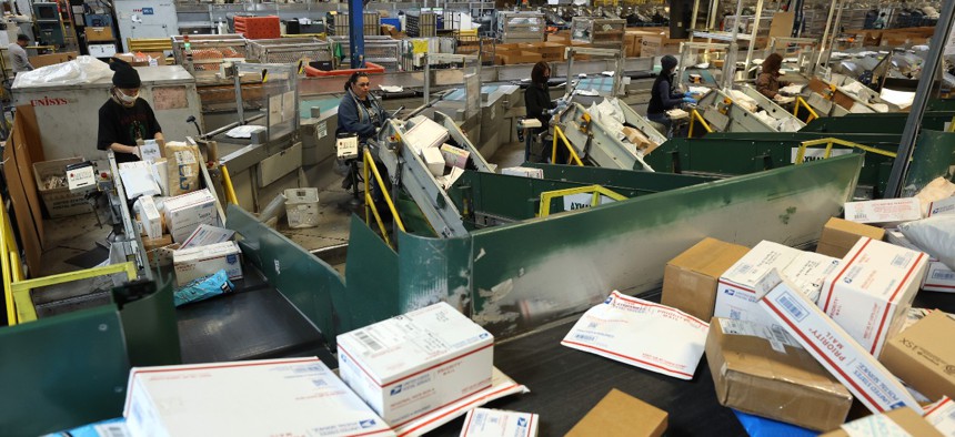 Workers sort packages at the U.S. Postal Service Processing And Distribution Center in San Francisco, California on December 14, 2022. USPS is launching a new shipping offering that officials say will be easier to use and more reliable. 