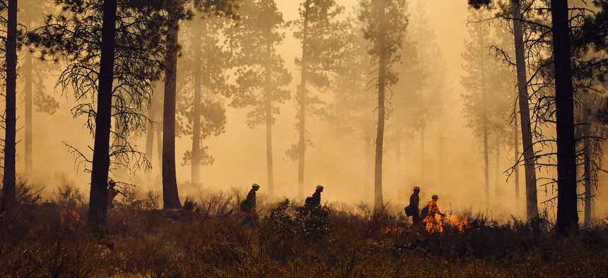 Federal firefighters combat a wildfire in 2014. The bill makes 2022 pay raises permanent by creating a special pay rate for federal firefighters.
