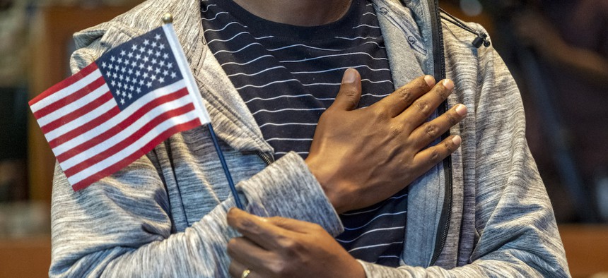 People hold flags during a U.S. Citizenship and Immigration Services' administration of the Oath of Allegiance ceremony at the Los Angeles Public Library on Oct 27, 2021. 