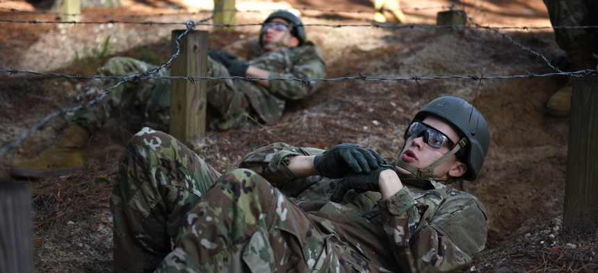 Army infantry recruits crawl under barbed wire as part of the confidence course on Fort Benning, Georgia, March 29, 2023.