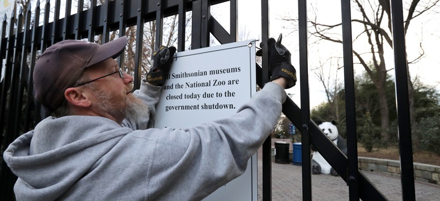 A Smithsonian National Zoo employee removes a sign telling visitors that the zoo is closed due to a government shutdown from the front gate on Jan. 28, 2019. 