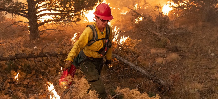 A firefighter uses a drip torch to ignite slash piles on the Bureau of Land Management's Trout Springs Prescribed Fire in southwest Idaho in 2019.