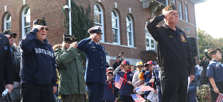 Veterans are seen saluting with Boy Scouts from Pack 406, of South Huntington, N.Y., during a Veterans Day Ceremony at Huntington Town Hall on Nov. 5, 2023. 