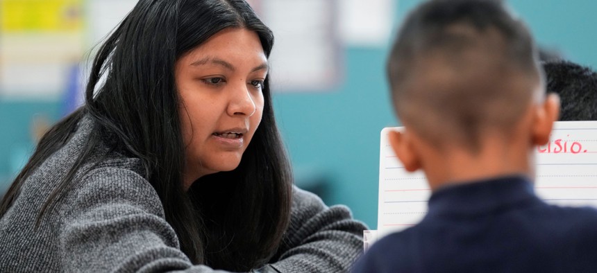 A dual language program pre-k teacher helps a student with his classwork on Monday, Nov. 27, 2023 at Gregg Elementary School in Houston.