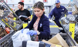 U.S. Postal Service employees place packages into a new package sorting machine, ahead of the holiday mail rush at the Torrance Post Office on Nov. 27, 2023 in Torrance, California.