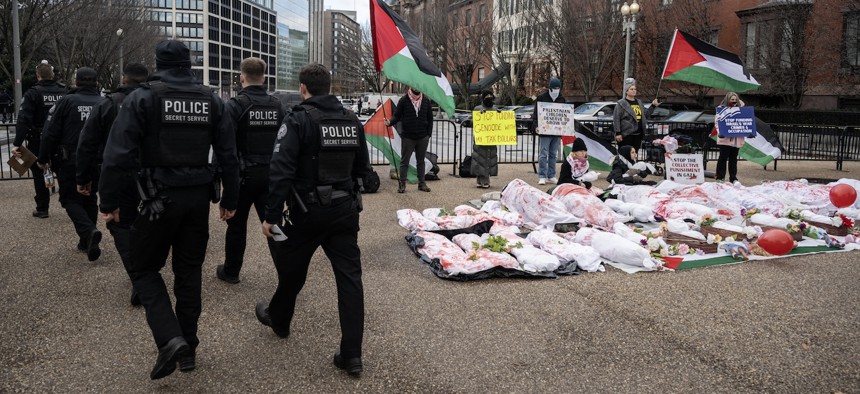 Members of the Secret Service walk past anti-war protesters demonstrating in support of Palestinians in Gaza, holding signs and waving flags near the White House on Dec. 11, 2023.