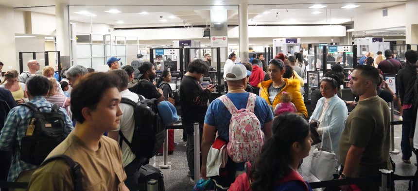 Travelers queue for security screening at San Diego International Airport.