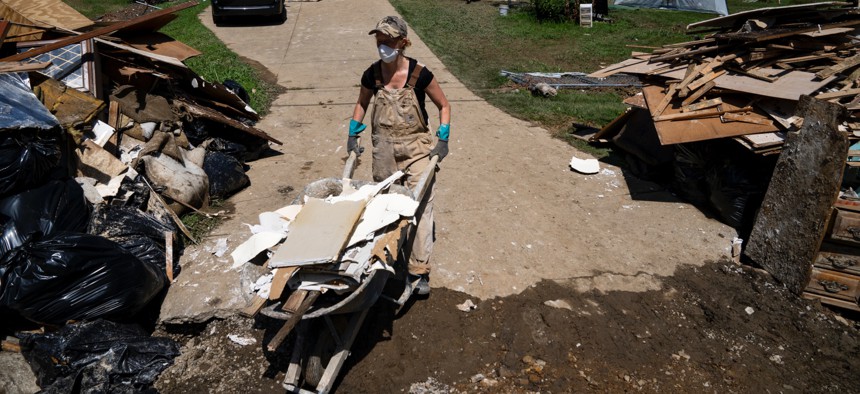 Laura Humphrey walks a wheelbarrow to a pile of debris while volunteering to clean up in Perry County, Kentucky near Hazard on Aug. 6, 2022. 