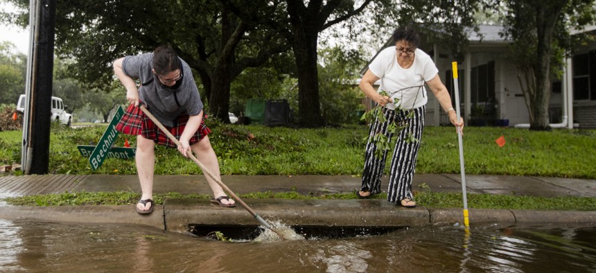 Residents help clear neighborhood drains after Hurricane Beryl made landfall early morning on July 8 in Houston. 