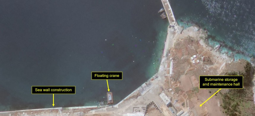 Construction activity on coastal seawall and submarine storage and maintenance hall near L-shaped pier on imagery from April 27, 2024