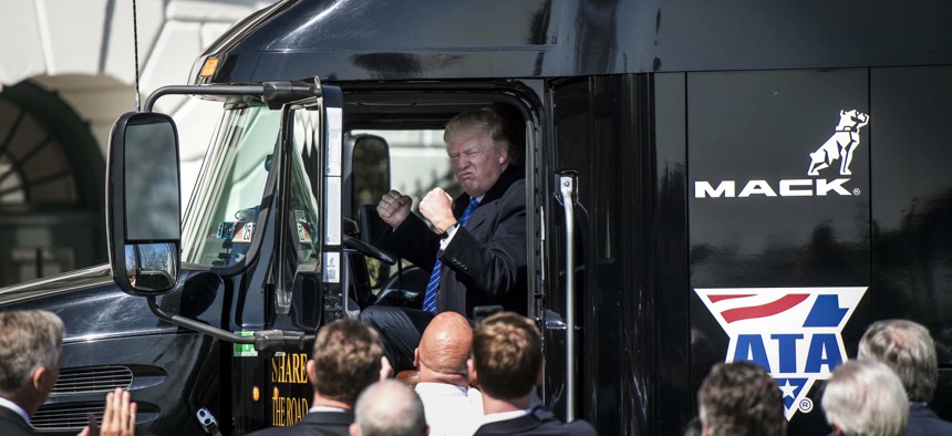 Then-President Donald Trump jumps up in the cab of an 18 wheeler truck while meeting with truckers and CEOs regarding healthcare on the South Lawn of the White House in 2017.