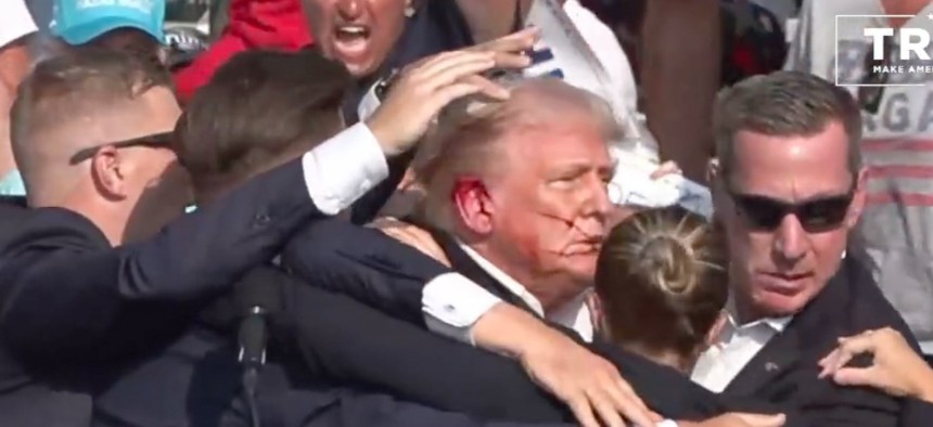 Former President Donald Trump is surrounded by U.S. Secret Service agents following an assassination attempt at a campaign rally in Butler, Pa., in July.