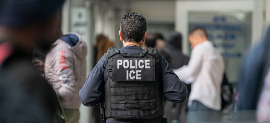 An ICE agent monitors asylum seekers being processed upon entering the Jacob K. Javits Federal Building in New York City, in June 2023.