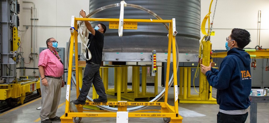 In this 2021 photo, Aerojet Rocketdyne employees prepare a manifold for the furnace as part of the process of manufacturing engines for NASAs Space Launch System rocket.