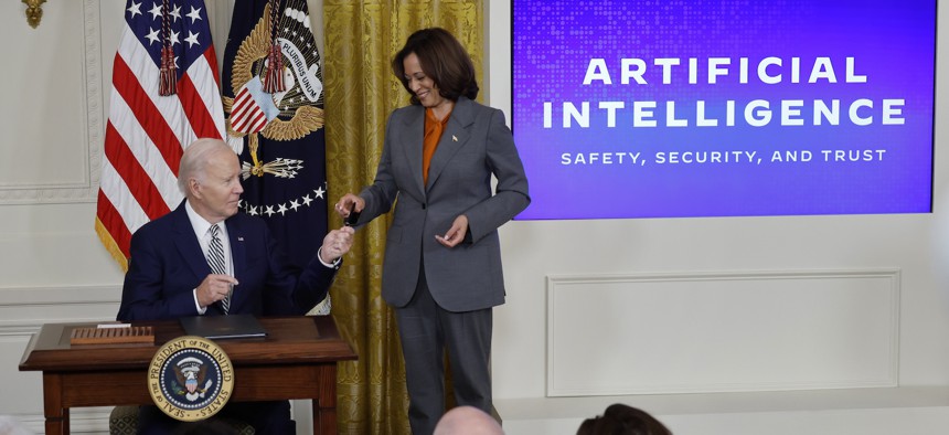 U.S. President Joe Biden hands Vice President Kamala Harris the pen he used to sign an executive order regarding artificial intelligence, Oct. 30, 2023. 