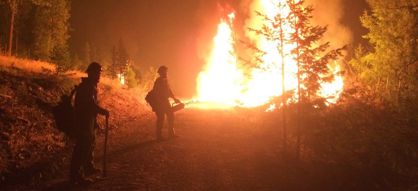 Two firefighters watch the flames during the Sunrise Fire in Western Montana in August 2017. 