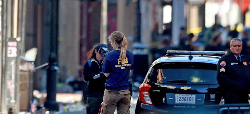 A member of the FBI's Evidence Response Team takes photographs on New Orleans' Bourbon Street following a New Year's Day attack in which an individual drove into a crowd. The FBI is surging agents to investigate the incident. 