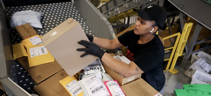 U.S. Postal Service mail clerk Quanika Davis sorts packages at the Royal Palm Processing and Distribution Center on Dec. 17, 2024 in Opa Locka, Florida.