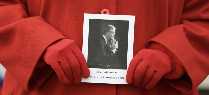 A person holds a photograph of former U.S. President Jimmy Carter after viewing his casket as he lies in repose at the Carter Presidential Center on Jan. 5, 2025 in Atlanta. Carter’s body will lie in state in the U.S. Capitol Rotunda until a funeral service at the National Cathedral in Washington on Jan. 9. 