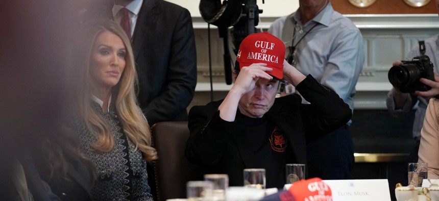 Elon Musk puts on a hat that reads "Gulf of America" during a Cabinet meeting at the White House on April 30, 2025. Recent surveys show that most Americans view his Department of Government Efficiency negatively.