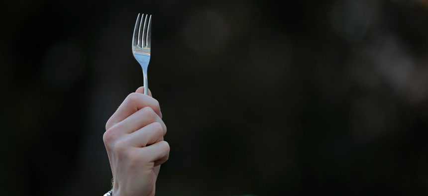 A protester holds a fork during a rally with federal workers and supporters as they demonstrate against Elon Musk and his Department of Government Efficiency (DOGE) outside of OPM headquarters on Feb. 07, 2025. The group protested several issues, including the "Fork in the Road" deferred resignation offer sent to OPM employees.