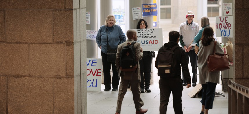 Supporters hold signs outside of the U.S. Agency for International Development as terminated employees come to collect their personal belongings on Feb. 27, 2025, in Washington, D.C. The Trump administration has aimed to shrink the size of the federal workforce, including nearly all of the staffers at USAID.
